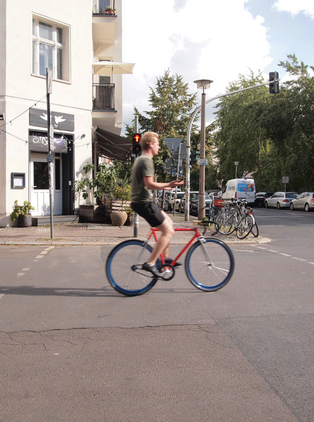 A guy riding a fixed gear bike on a sunny day.