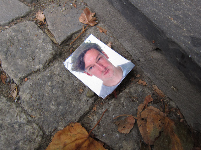 A lost passport photo of a young man lying on the ground.