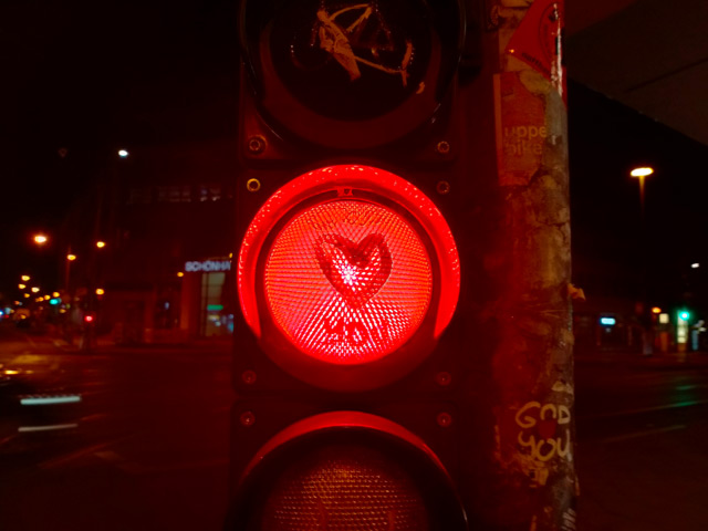 Someone has painted a graffiti with the words 'God Loves You' on a red traffic light.