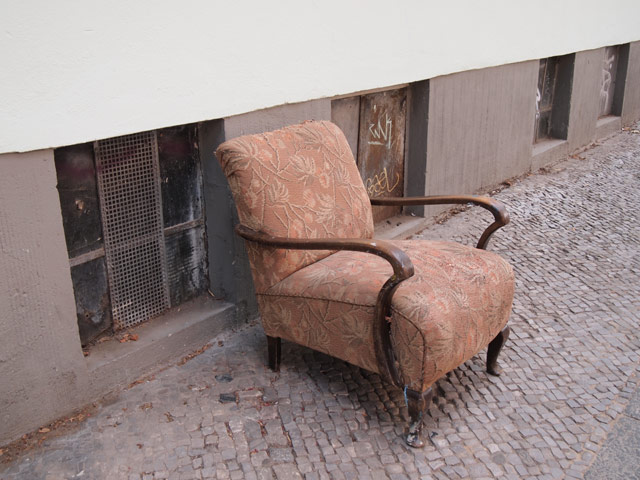 An old armchair, abandoned on the sidewalk.