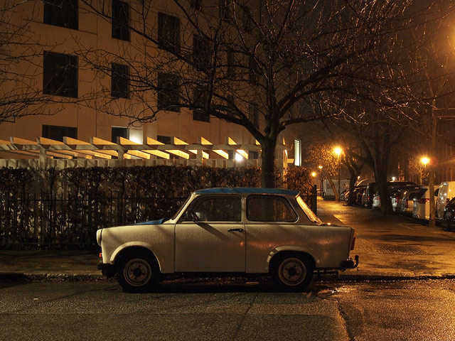 An old Trabant parked on the side of a rainy road.