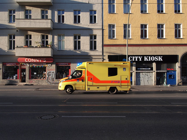 A yellow ambulance races down a street in Berlin.